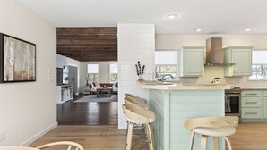 Una cocina moderna con una isla central, taburetes de bar y vista al comedor.