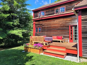 Une cabane en bois dotée d’une terrasse, d’un espace salon extérieur et d’un jardin.