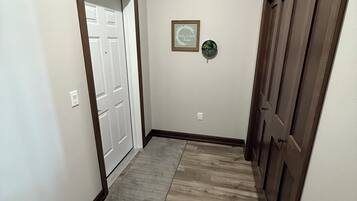 A hallway with a wooden door, a welcome sign, and a small potted plant.