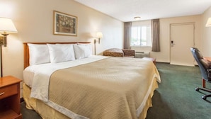 Una habitación de hotel con una cama grande, un escritorio, una silla, una ventana y una puerta.