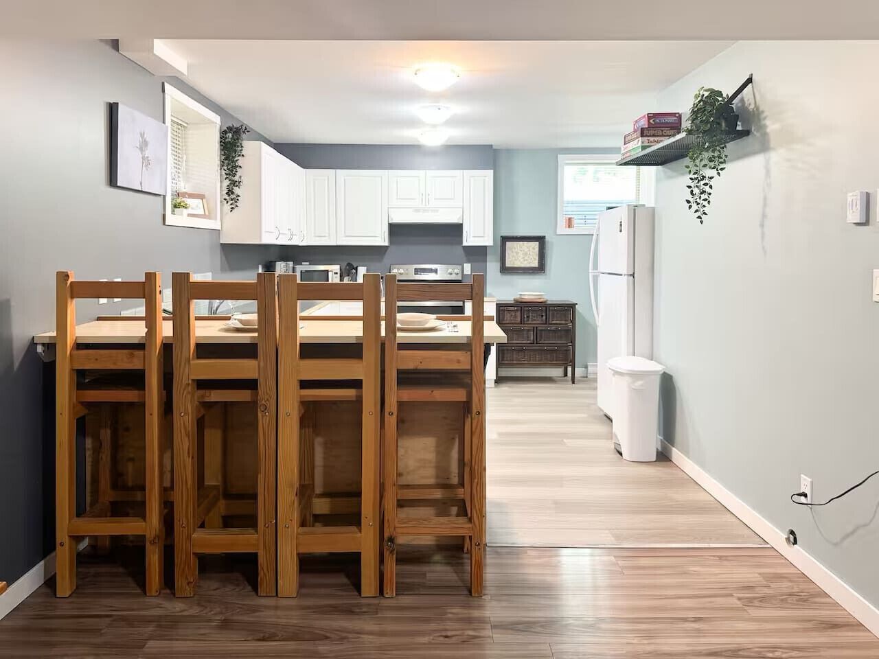 Une cuisine moderne avec des meubles blancs, une table à manger en bois et un micro-ondes encastré.