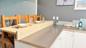 Una cocina moderna con una mesa de comedor de madera, armarios blancos y un salpicadero gris.