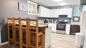 Una cocina moderna con armarios blancos, una mesa de comedor de madera y un horno empotrado.