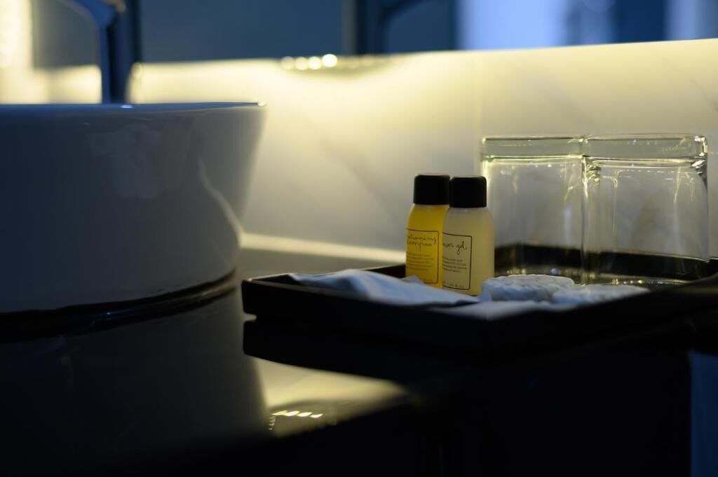 A hotel room with a coffee maker, a tray with two bottles of hand sanitizer, and a glass of water.