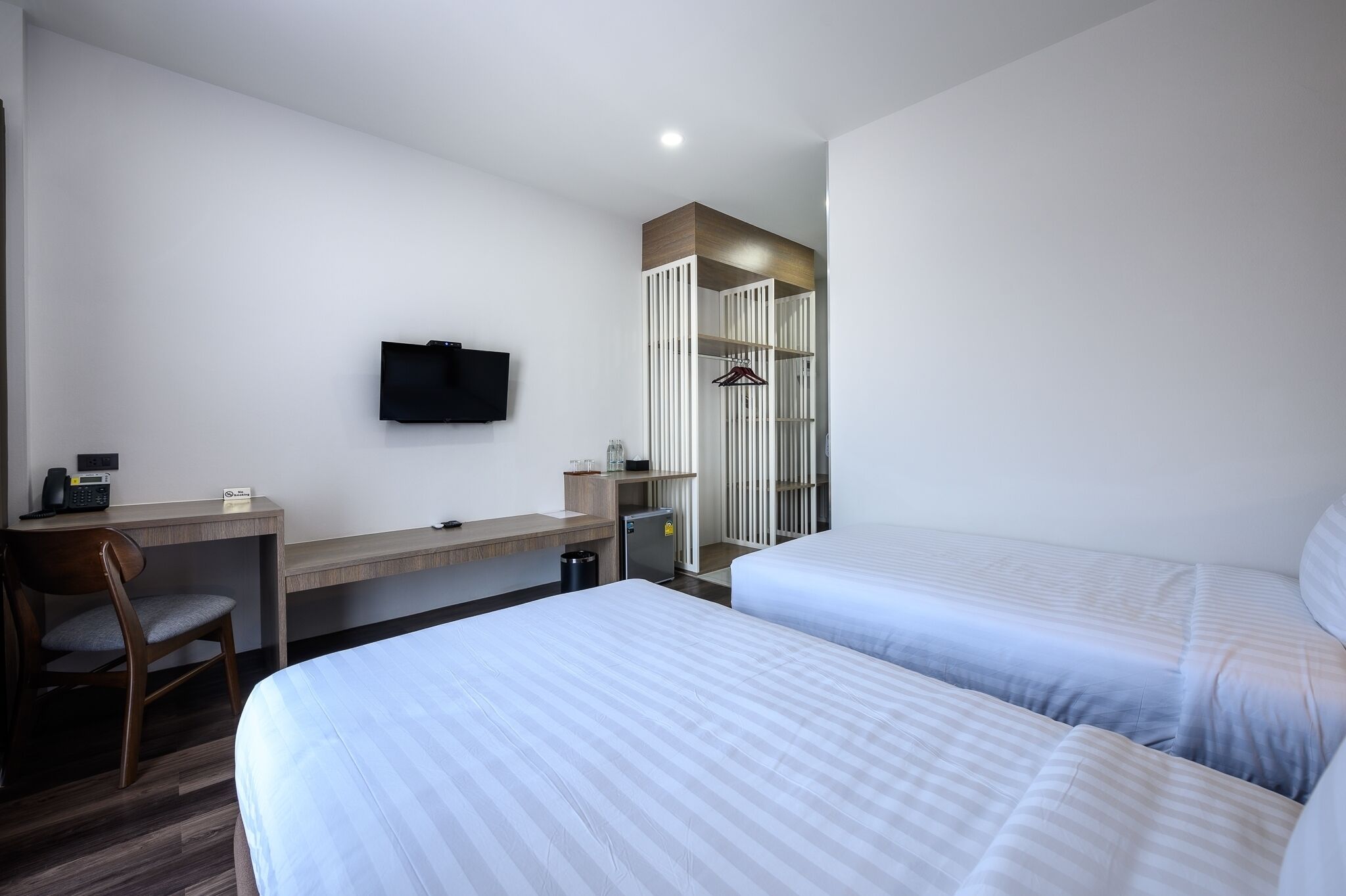 Habitación de hotel con dos camas, un escritorio, una silla, un televisor y un armario.