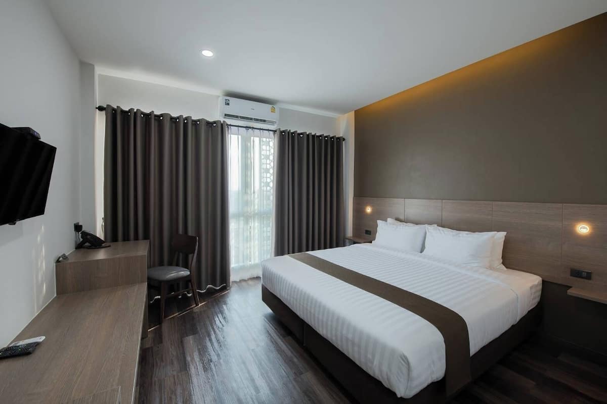 Een moderne hotelkamer met een groot bed, een bureau met stoel en een flatscreen televisie.