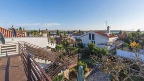 Un barrio residencial con una casa blanca, una terraza de madera y un cielo azul despejado.