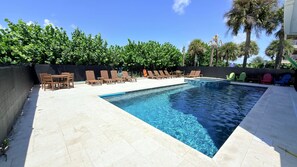 Una piscina con sillas de descanso y un suelo de baldosas.