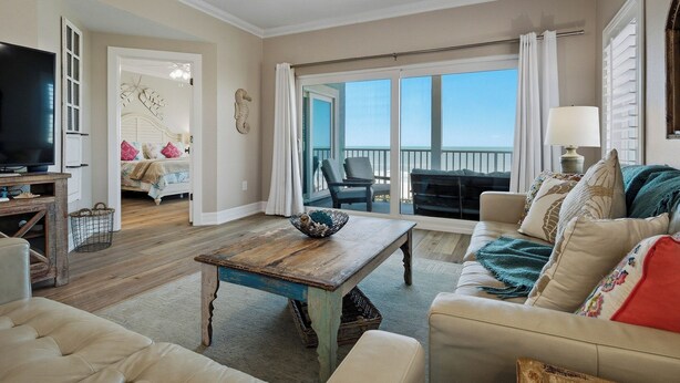 A spacious living room with a large TV, a wooden coffee table, and a sofa. - Beachfront, Tropical Paradise, Intimate Complex, EV Charger! (Indian Rocks Beach)