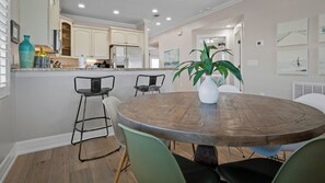 Un comedor con una mesa redonda de madera, sillas verdes y una planta en maceta.