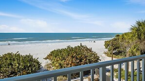 A beach with a railing, ocean view, and some greenery. - Beachfront, Tropical Paradise, Intimate Complex, EV Charger! (Indian Rocks Beach)