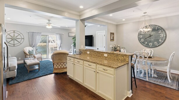 A spacious kitchen with a granite countertop, white cabinetry, and a large wall clock. - Coastal St. Simons Island Townhome Near Beaches, Shopping & Dining (Saint Simons Island)
