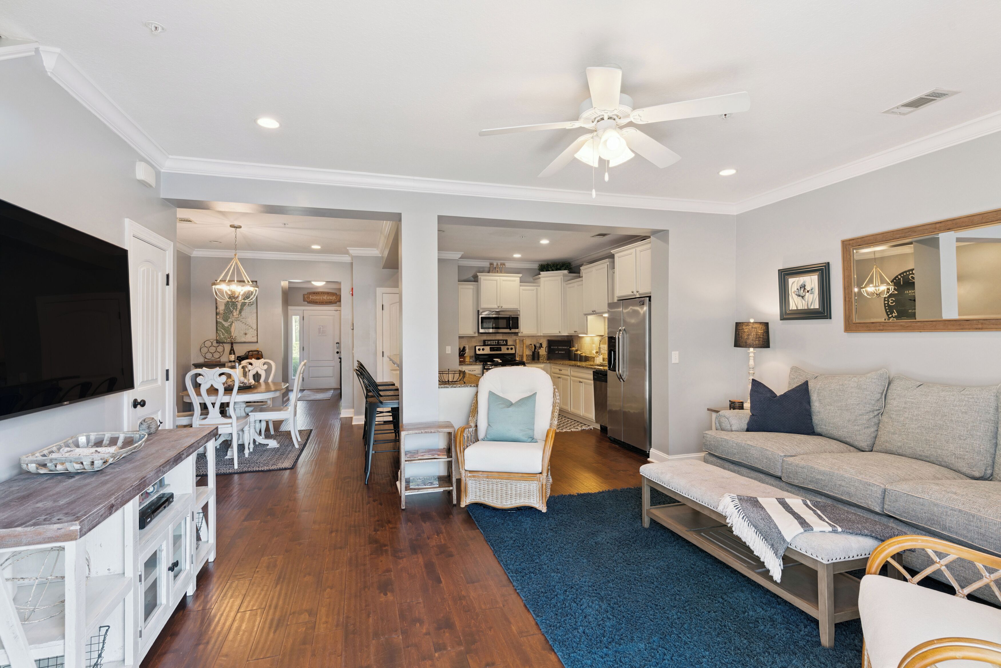 A spacious living room with a large TV, a ceiling fan, and a sofa.