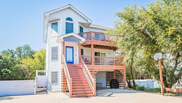 A two-story house with a front porch, a staircase, and a basketball hoop. - Knot A Care - Corolla, Ocean Sands, 400 Yds to Beach, Pool, Hot Tub, Pool Table, Pets OK (Corolla)