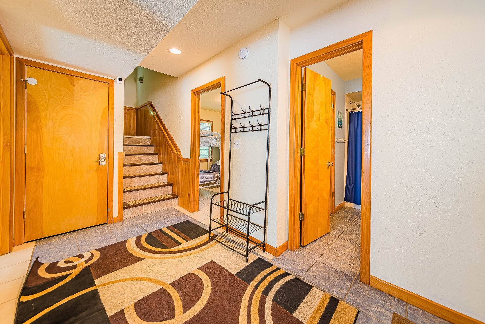 A hallway with wooden doors, a staircase, and a metal rack.