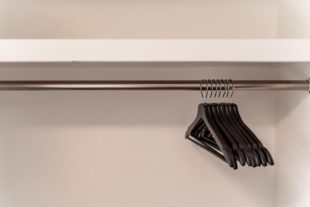 A closet with a metal rod and black hangers.