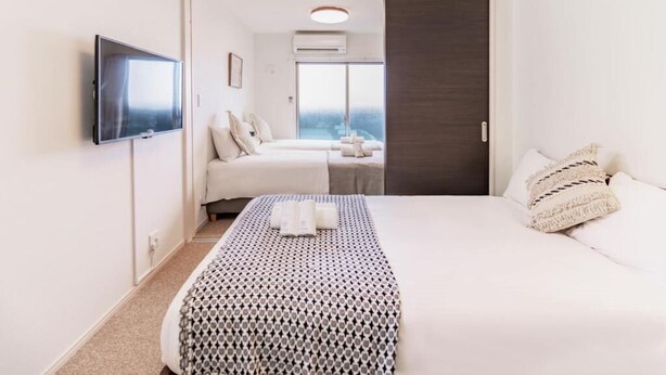A hotel room with a bed, a TV, a window, and a door. - Chuan House Asahi (Osaka)