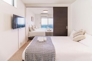 A hotel room with a bed, a TV, a window, and a door. - Chuan House Asahi (Osaka)