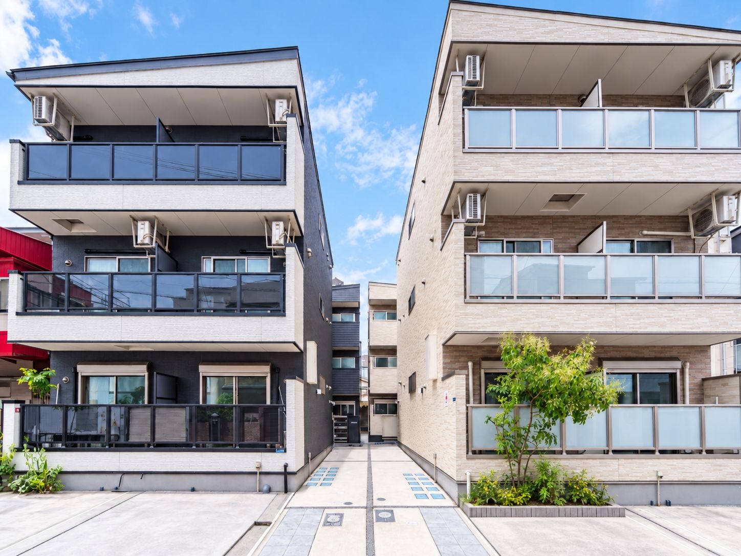 A modern apartment building with balconies, large windows, and air conditioning units.