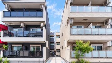 A modern apartment building with balconies, large windows, and air conditioning units.