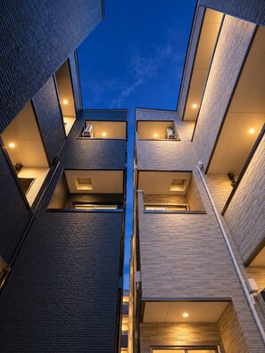 A multi-level building with balconies and a central open space. - Chuan House Asahi (Osaka)