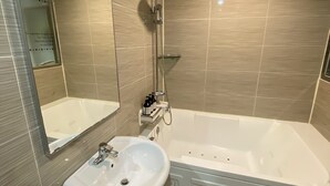 Une salle de bain moderne avec une grande baignoire, un lavabo et une douche.