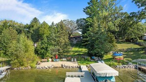 A lakeside property with a dock, a covered boat, and a grassy area with trees. - Lakefront Getaway, Swim, Laugh, Family Fun for all! Close to Kettle Moraine (Palmyra)