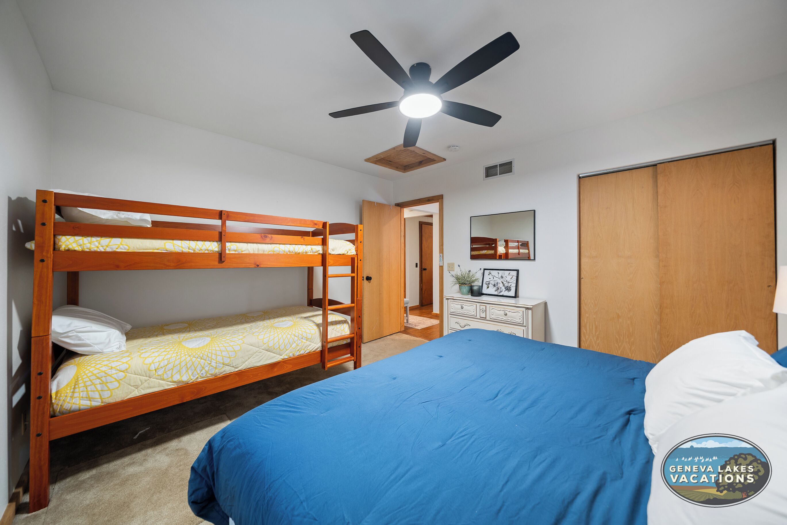 A bedroom with bunk beds, a ceiling fan, a dresser, and a wardrobe.