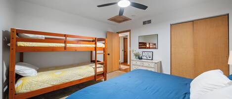 A bedroom with bunk beds, a ceiling fan, a dresser, and a wardrobe.