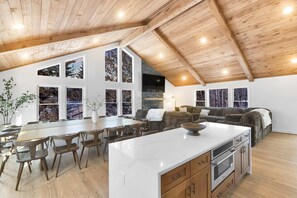 A spacious living area with a large wooden ceiling, a central island with a sink, and a seating area with a sofa and chairs. - ELK COVE - Modern Pocono Cabin - Pool - Pickleball (Blakeslee)