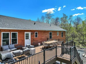A wooden cabin with a deck, outdoor seating, and a staircase leading to a second level. - ELK COVE - Modern Pocono Cabin - Pool - Pickleball (Blakeslee)