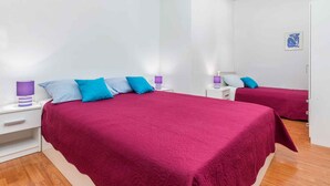 Camera da letto con due letti, ciascuno con copripiumino rosso e numerosi cuscini. Sono presenti comodini con lampade e un piccolo quadro appeso al muro.