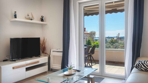 Ein modernes Wohnzimmer mit Flachbildfernseher, Glastisch und Balkon mit Blick.