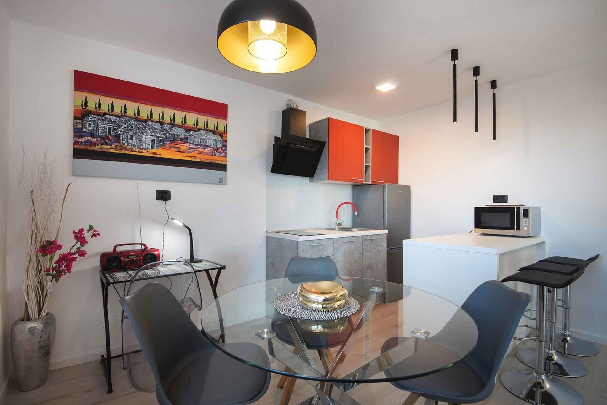 Une cuisine moderne avec une table à manger en verre, des placards rouges et un four à micro-ondes.