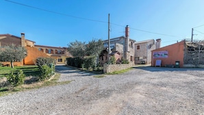 A rural setting with a gravel driveway leading to a stone building with a signboard. - Holiday home with air conditioning (Vodnjan)