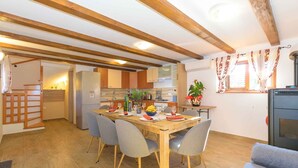 A dining area with a wooden table, grey chairs, and a kitchen in the background. - Holiday home with air conditioning (Vodnjan)