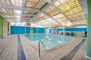 Une piscine intérieure à l’eau claire, dotée d’un sol carrelé et d’un plafond agrémenté de lucarnes.