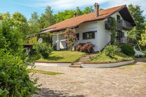A two-story house with a red-tiled roof, a balcony on the second floor, and a stone-paved driveway leading to the entrance. - Villa with heated pool and air conditioning (Cerovlje)