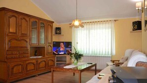 Una sala de estar con un aparador de madera, un televisor, una mesa de centro y un sofá.