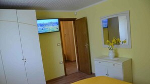 Un dormitorio con cama, armario, televisor y espejo decorado con flores.