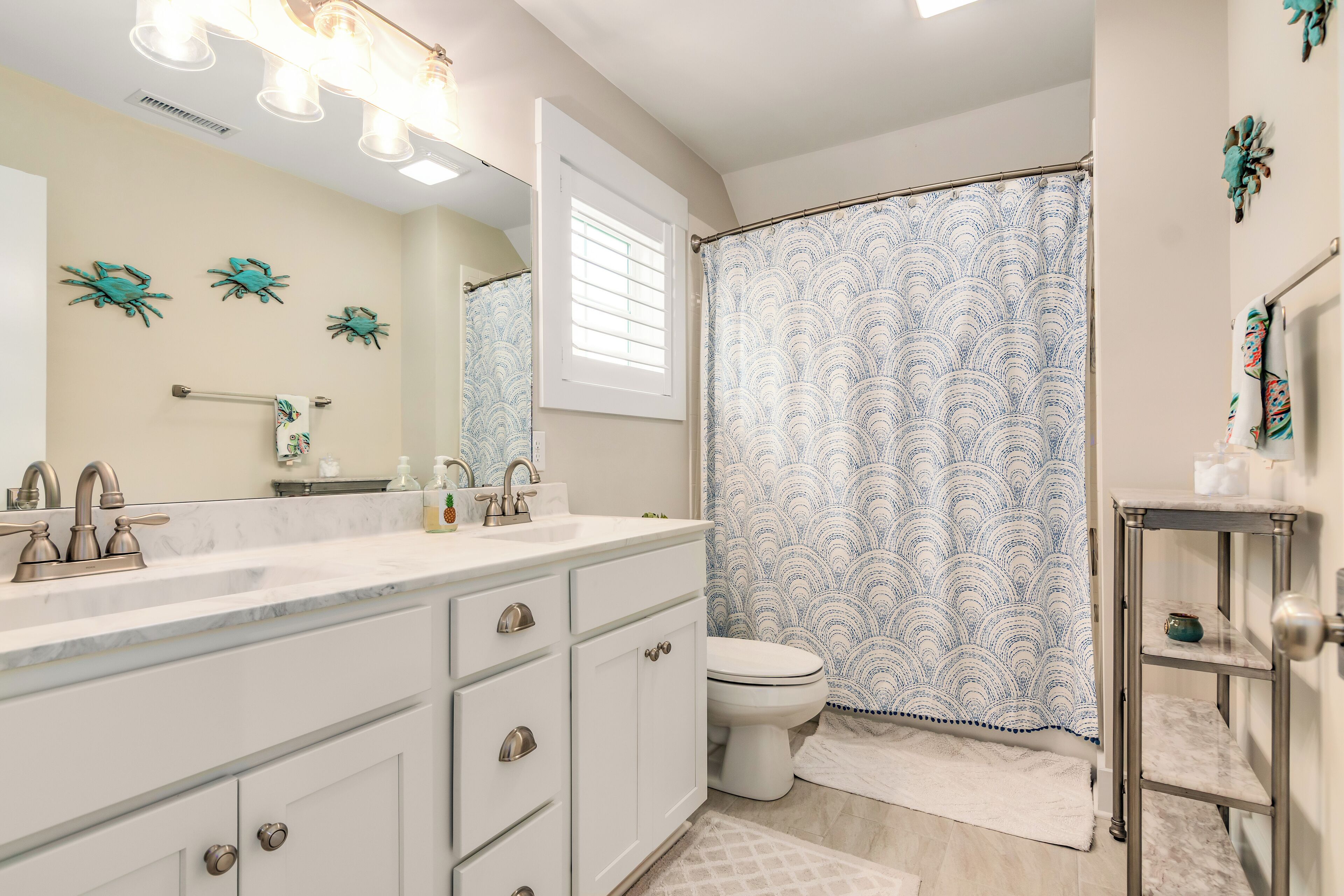 Une salle de bain avec un meuble-lavabo blanc, un évier, des toilettes et un rideau de douche à motifs bleus.