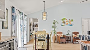 A modern kitchen with a dishwasher, a dining area with a table and chairs, and a living area with a sofa and chairs. - Laid-Back Beachfront Bungalow (Galveston)