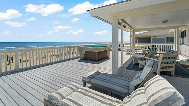 A wooden deck with lounge chairs and a pool table, overlooking the ocean. - Laid-Back Beachfront Bungalow (Galveston)