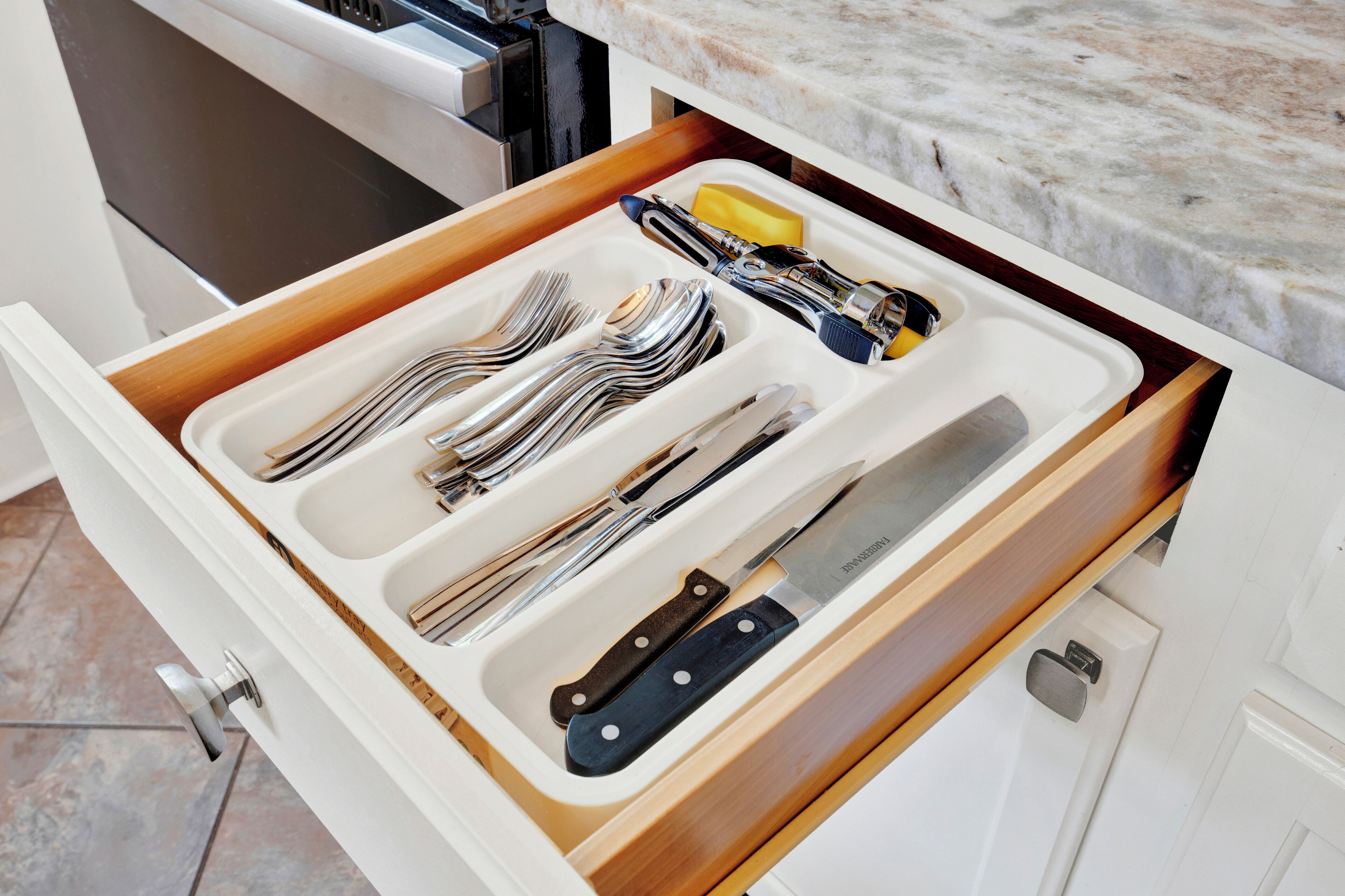 A drawer with utensils and a knife.