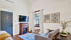 Una sala de estar con chimenea, televisor, sofá y una mesita.