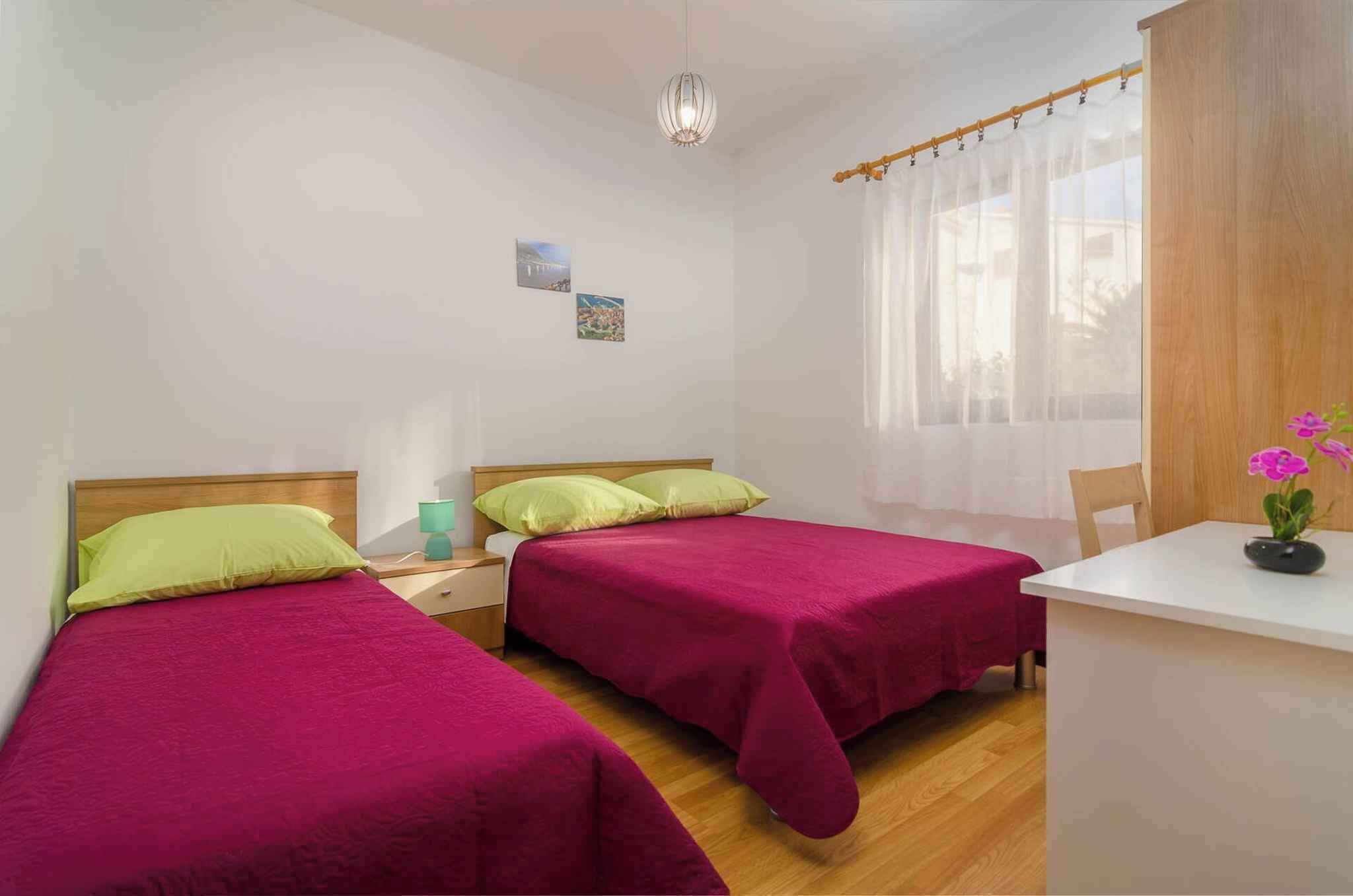 Een kamer met twee bedden, een klein tafeltje en een raam met dunne gordijnen.