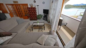 Olohuoneessa on sohva, sohvapöytä, televisio ja näkymä järvelle.