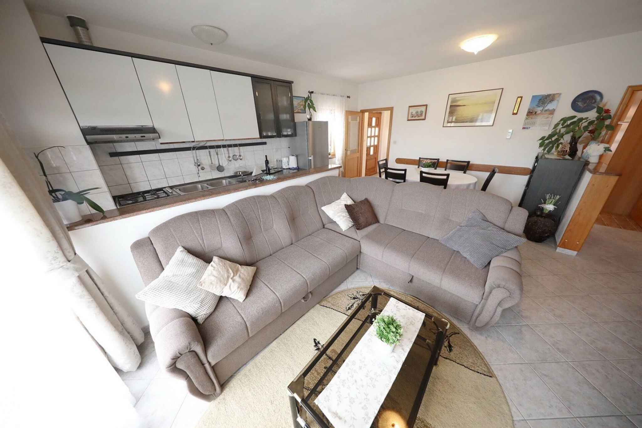 A living room with a sofa, a coffee table, and a kitchen area in the background.