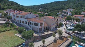 Un pueblo costero con arquitectura tradicional, un puerto deportivo con barcos y un paisaje de colinas al fondo.