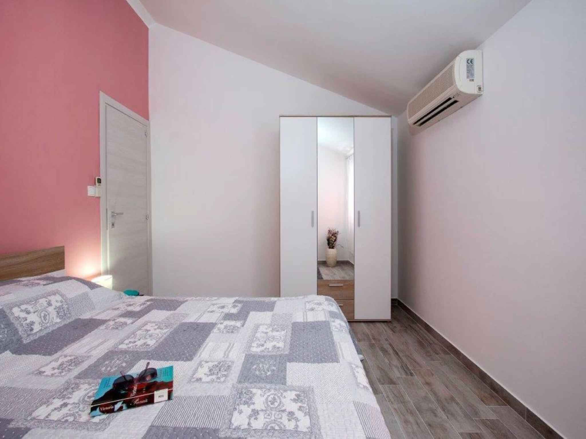 Quarto com cama, guarda-roupa e ar condicionado.